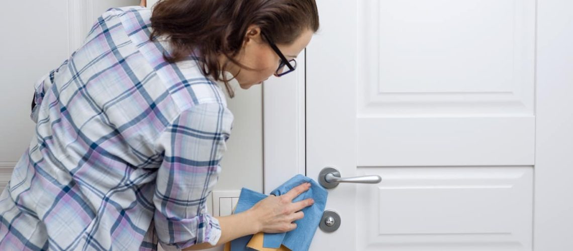 femme qui nettoie une porte d'entrée en pvc